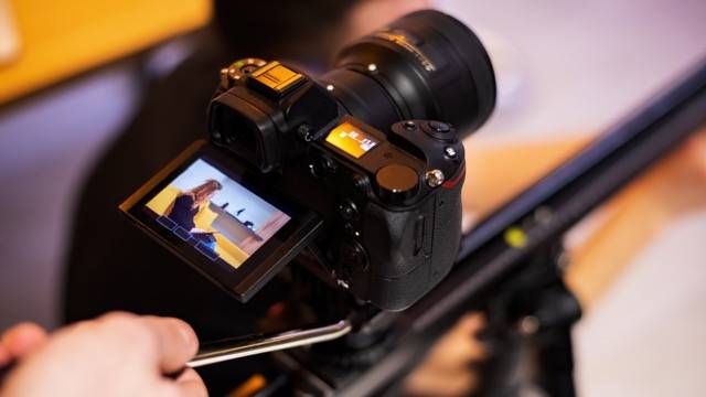 Camera on a tripod shooting a young girl with tablet on sofa. Working from home